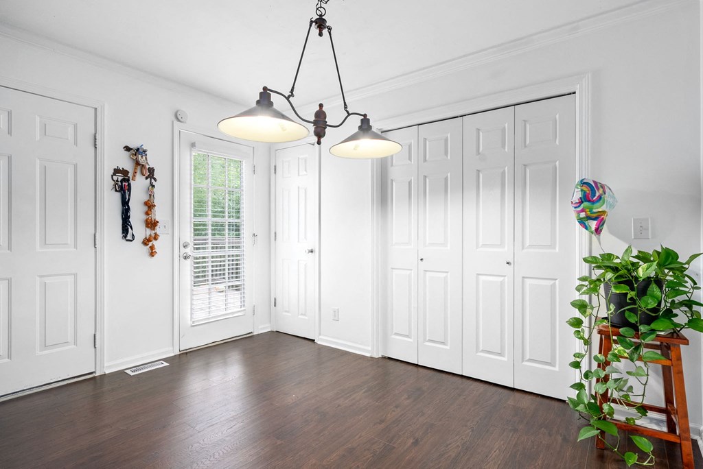 an empty living room with white walls and wood flooring and a potted plant