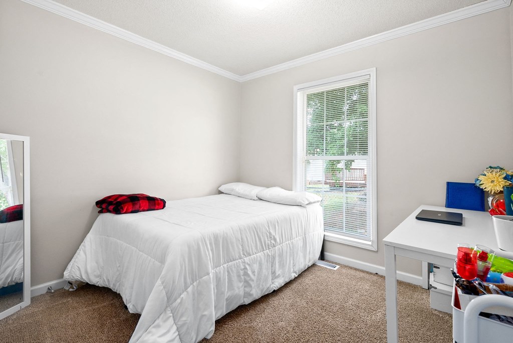 a bedroom with a bed and a desk and a window