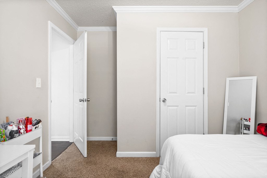 a bedroom with a white bed and two closet doors