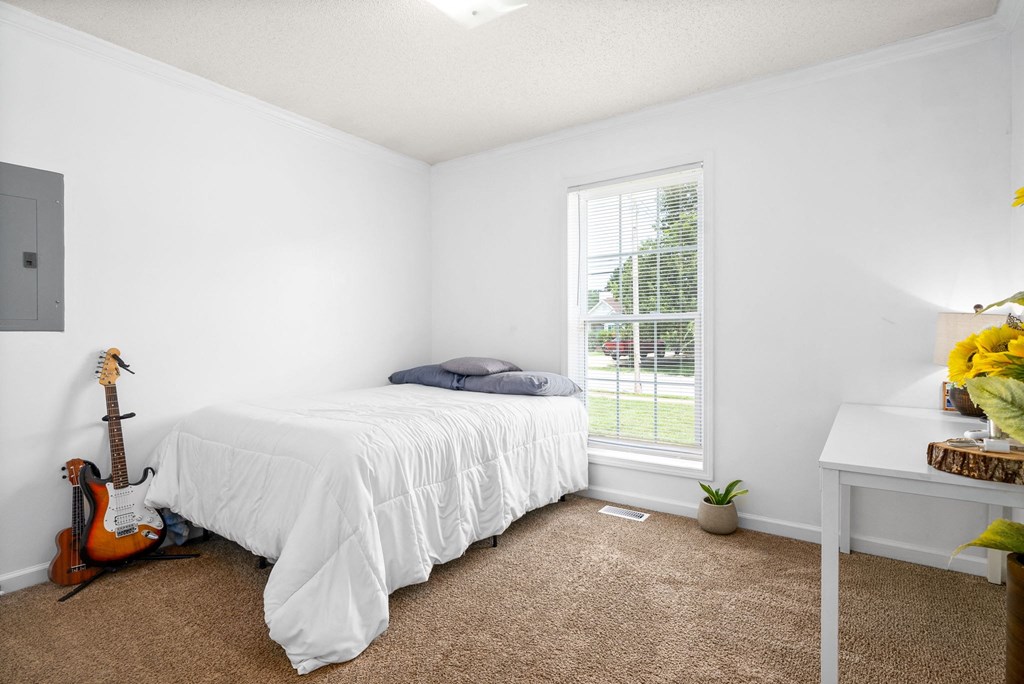 a bedroom with a bed and a guitar on the floor