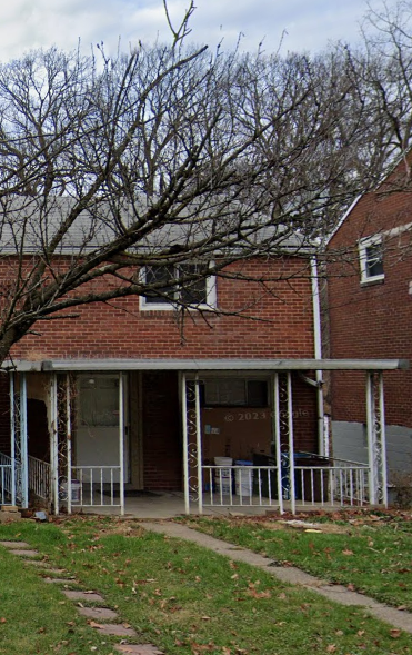a building with a porch and a tree in front of it
