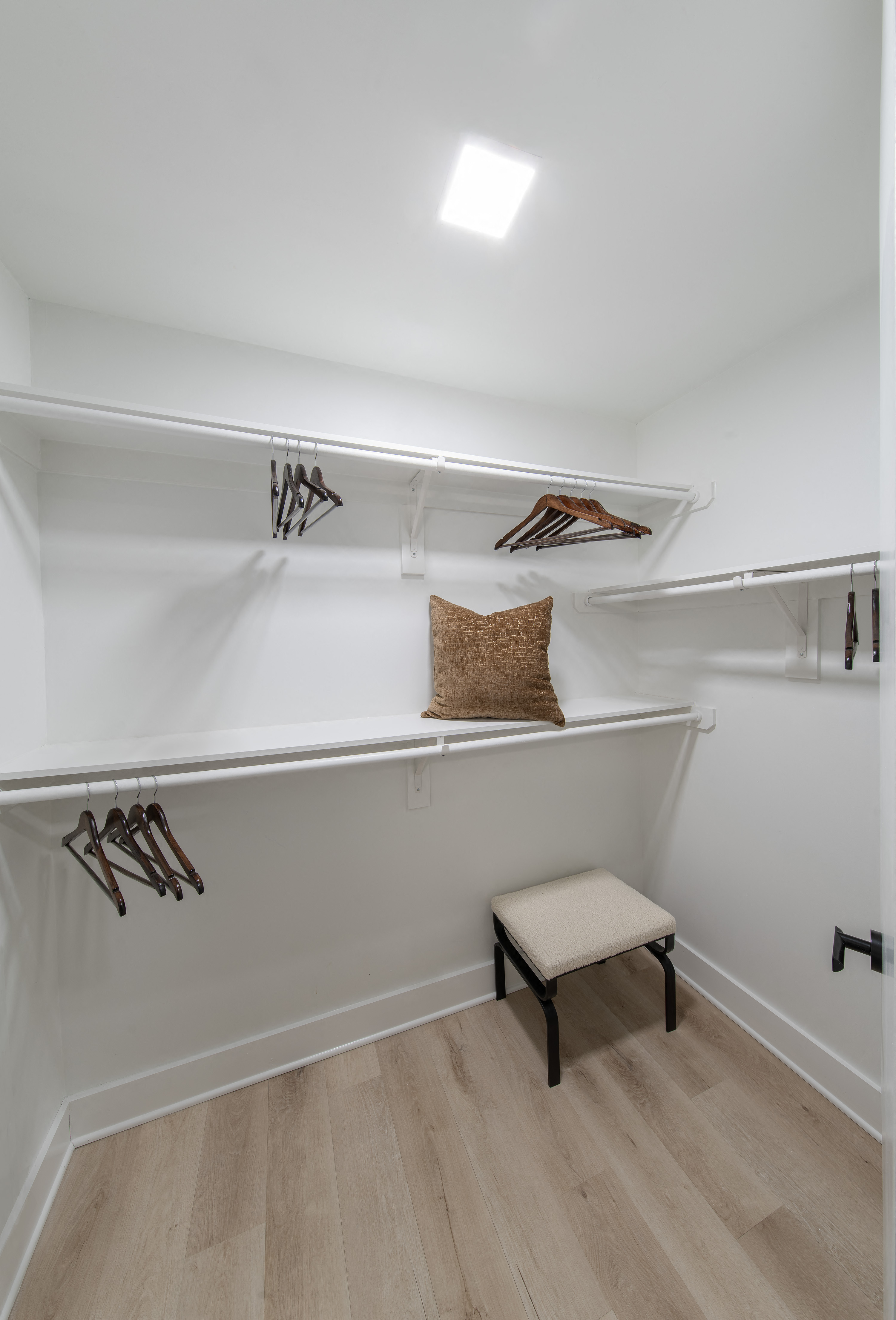 a walk in closet with a shelf and a chair and a pillow