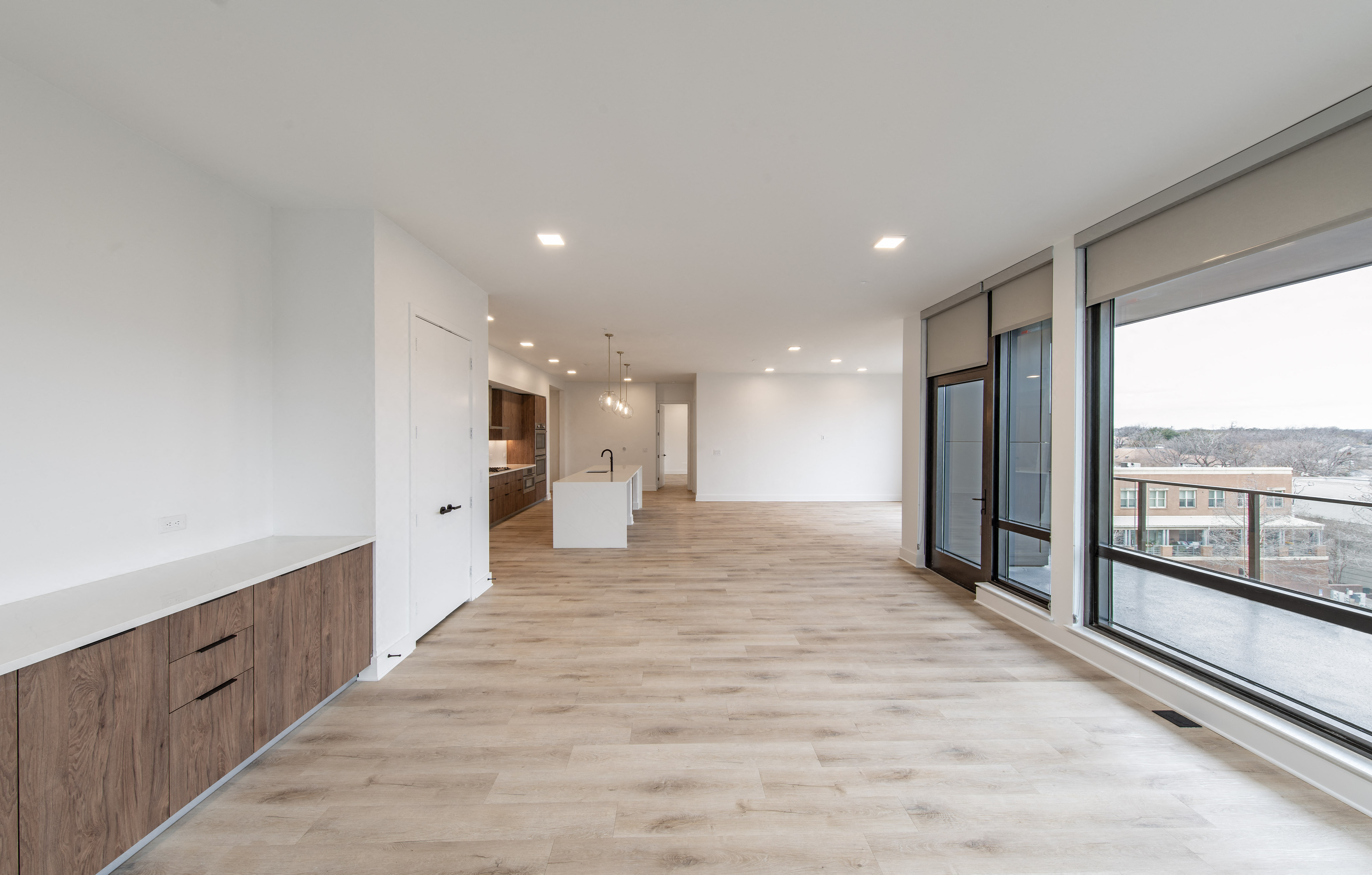 a long hallway with large windows and white walls and wood floors