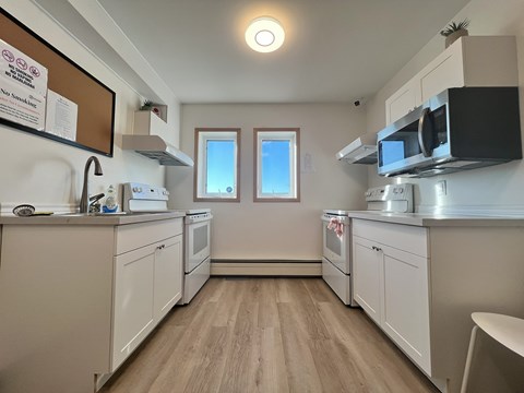 A kitchen with white cabinets and a microwave above the stove.