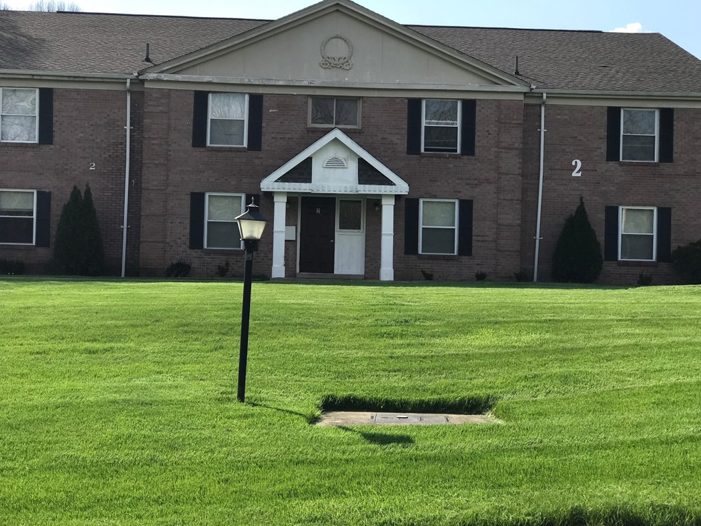 the front of a brick house with a lamp post in the grass