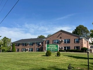 A building with a sign that says Greene Meadows in front of it.