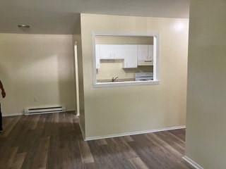 A room with a kitchen in the background and a window.