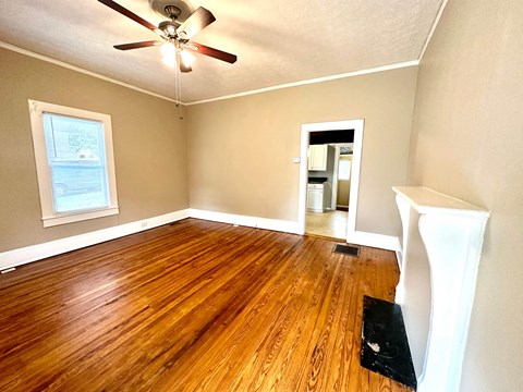 an empty living room with wood floors and a ceiling fan
