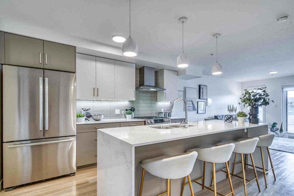 a kitchen with a marble counter top and white stools