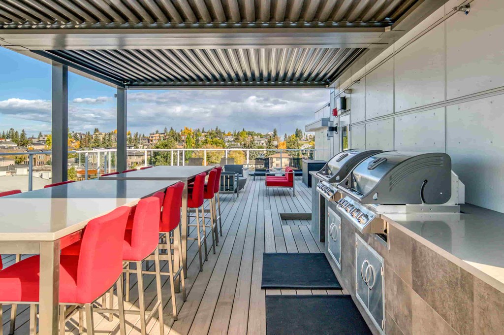 the outdoor deck of a restaurant with a grill and a table with red chairs