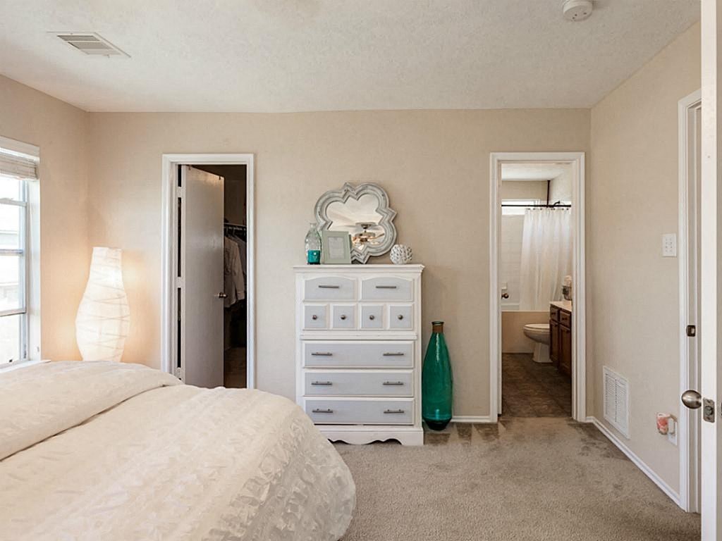 a bedroom with a bed and a dresser     and a bathroom