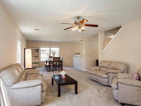 a living room with couches and a table and a ceiling fan
