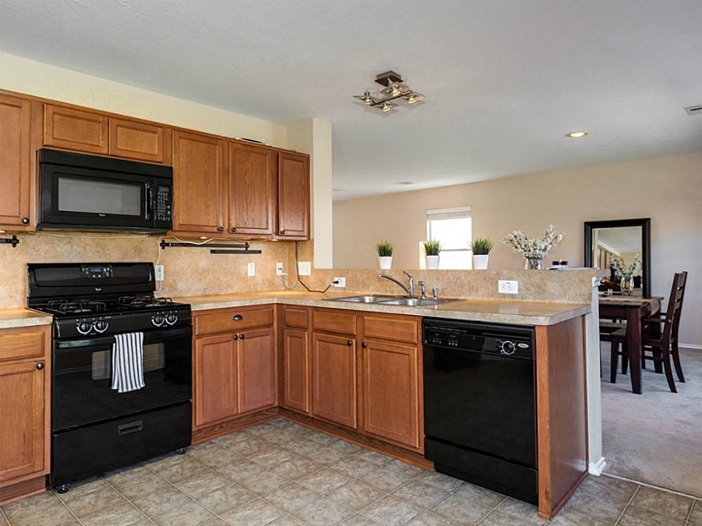 a large kitchen with black appliances and wooden cabinets