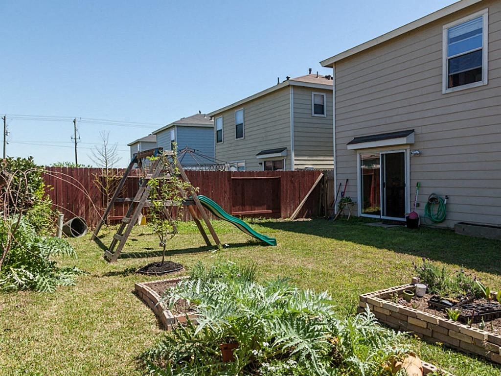 a backyard with a swing set and a fence