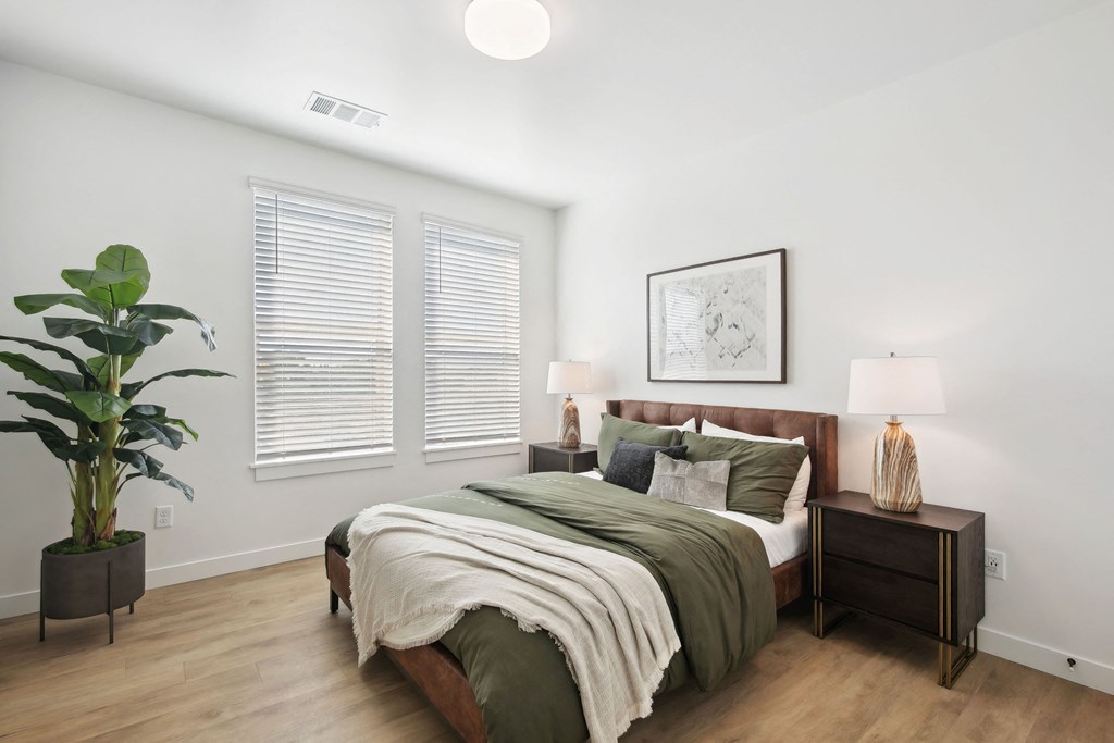 a bedroom with white walls and a bed with green blankets and pillows