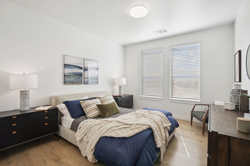 a bedroom with a bed and two windows