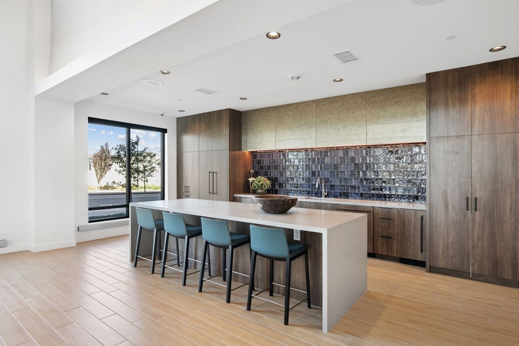 a kitchen with an island and blue stools in front of a large