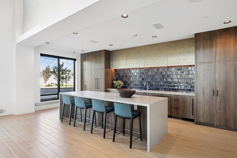 a kitchen with an island and blue stools in front of a large