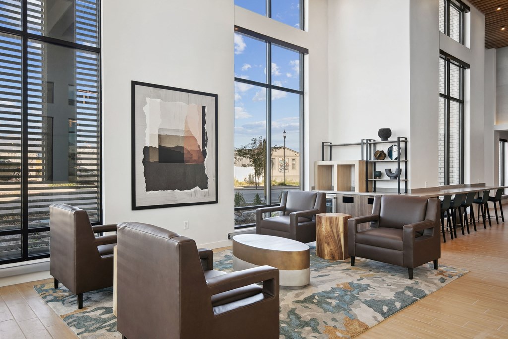 a living room with chairs and a table and large windows