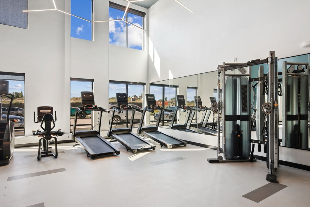a gym with cardio equipment and windows in a building