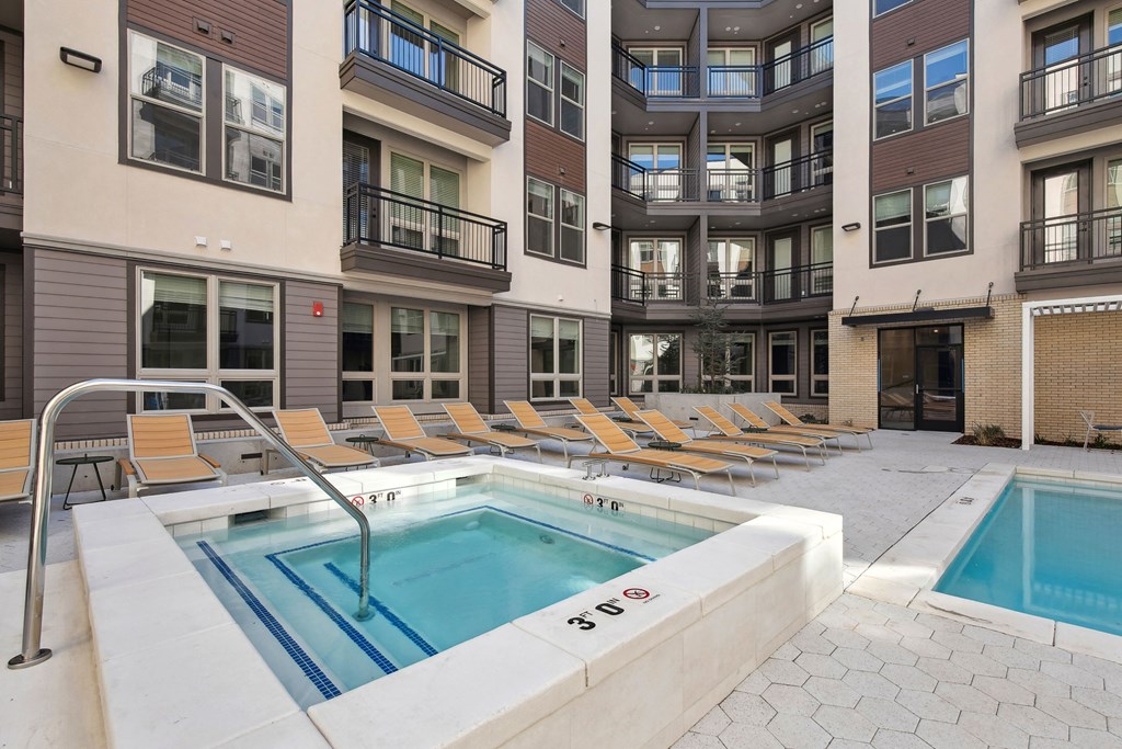 a pool with yellow chairs in front of an apartment building