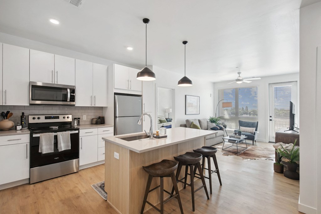 an open kitchen and living room with an island and stools