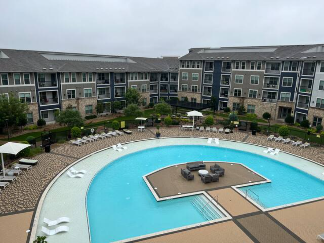 an aerial view of a large swimming pool in front of an apartment building