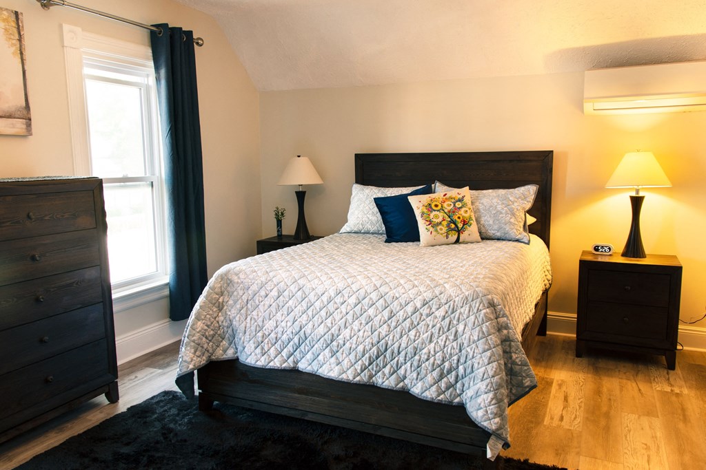 a bedroom with a bed and two night stands and a window