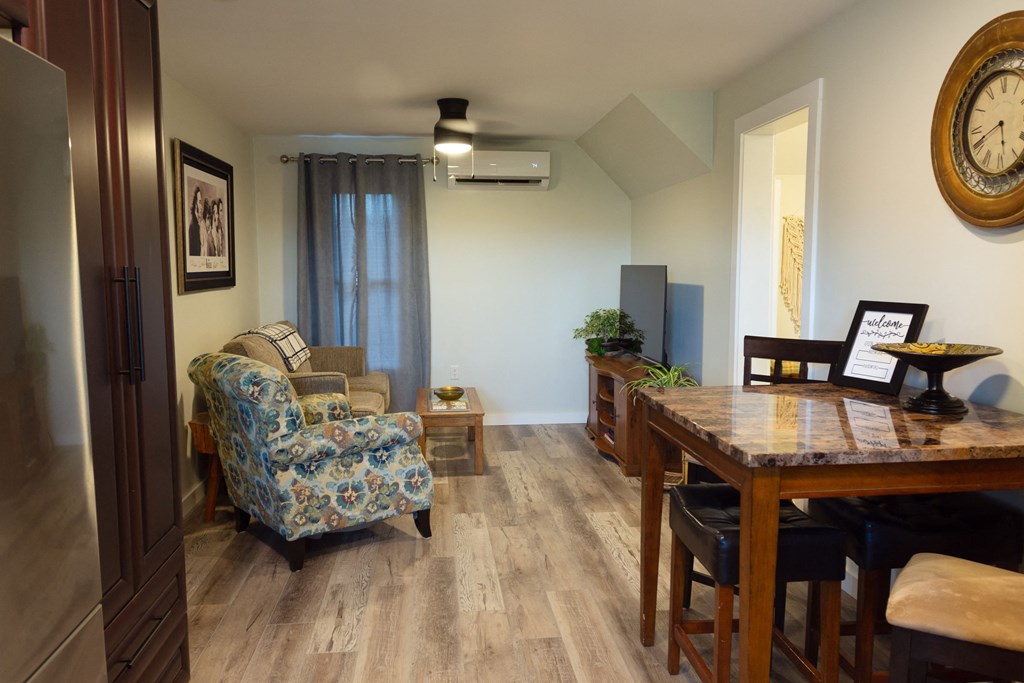 a living room and dining room with a wooden table and chairs and a large clock