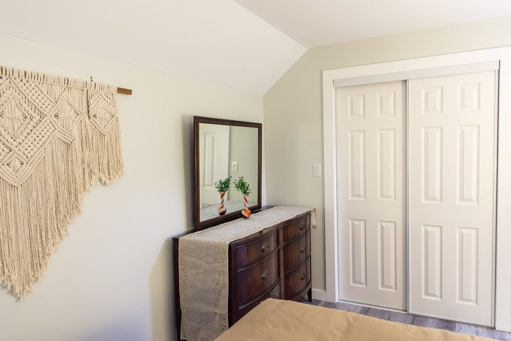 a bedroom with a dresser and a mirror on the wall