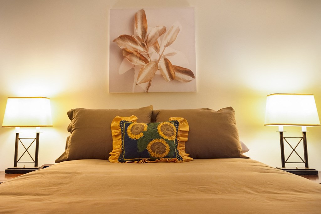 a bedroom with a bed and two lamps and a painting on the wall