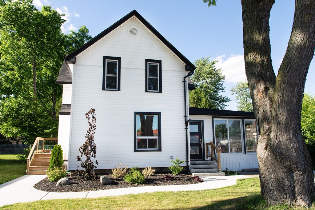the exterior of a white house with a yard and trees