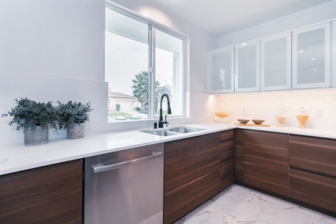 A modern kitchen with a stainless steel dishwasher and wooden cabinets.