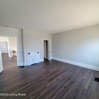 an empty living room with wooden floors and white walls