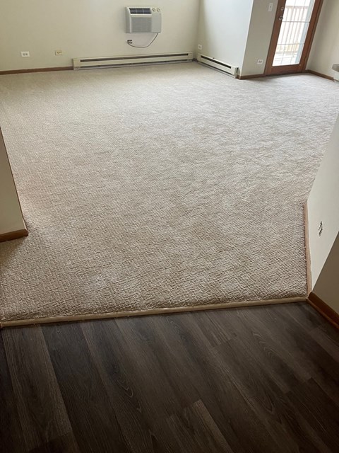 an empty room with a hard wood floor and a tan carpet