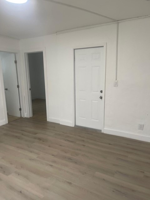 A room with a white door and a wooden floor.
