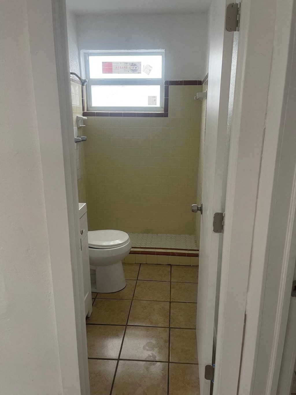 A bathroom with a toilet and a window.