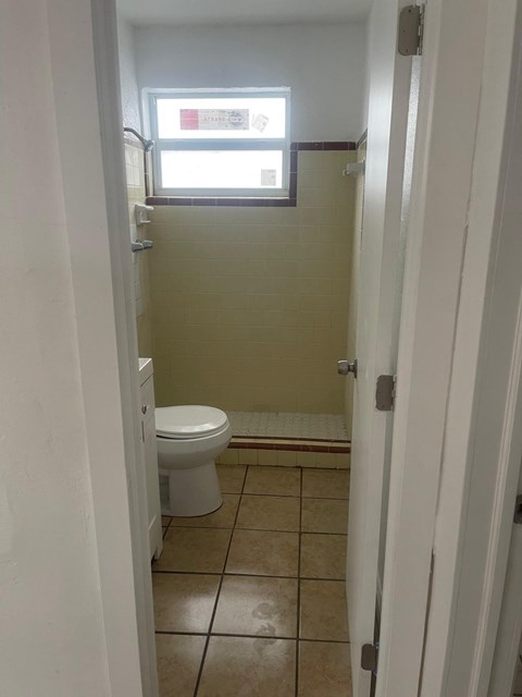 A bathroom with a toilet and a window.