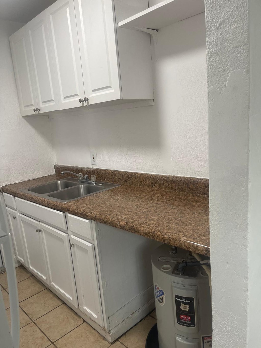 A kitchen with white cabinets and a granite countertop.