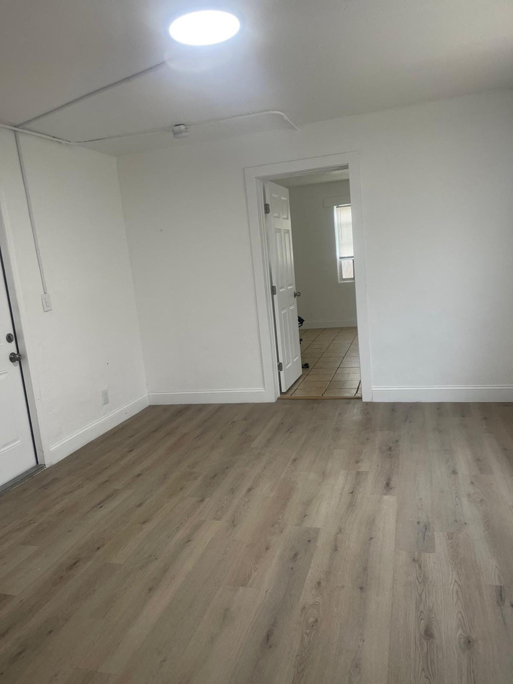 A room with wooden flooring and a doorway leading to another room.
