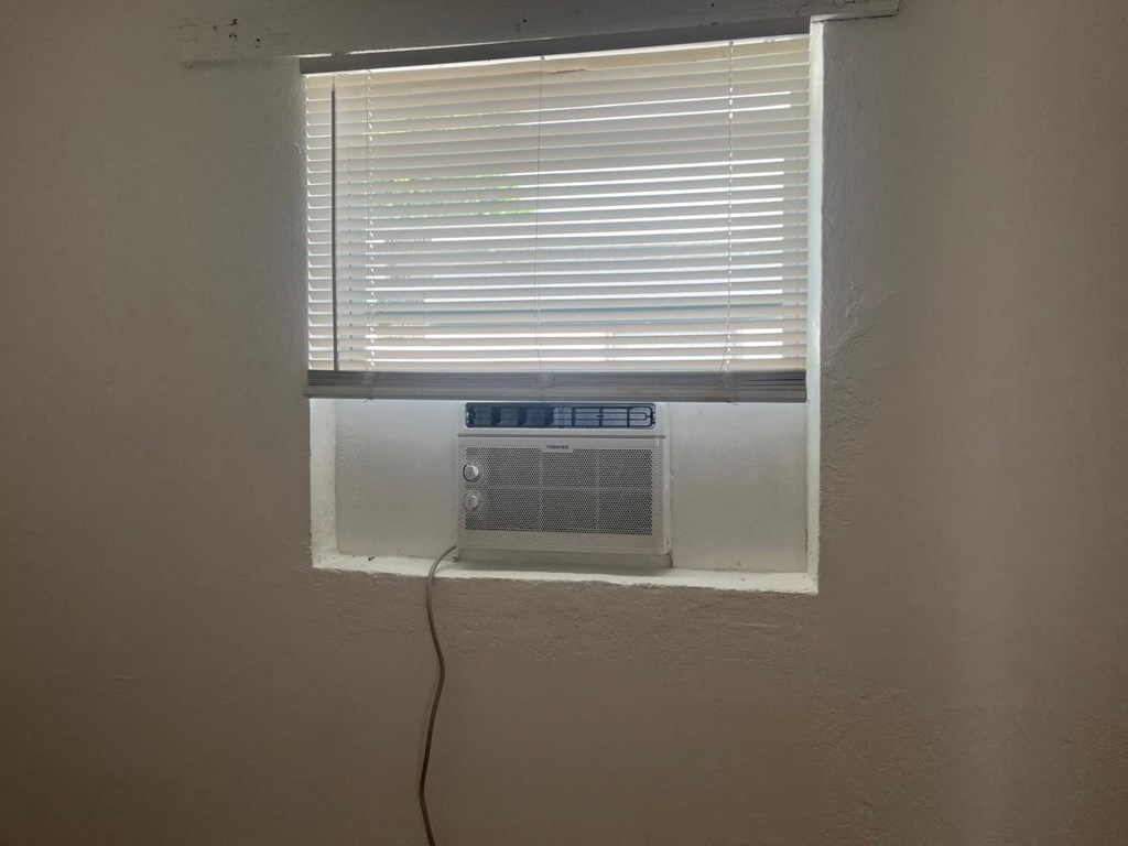 A window with blinds and a window air conditioner unit.