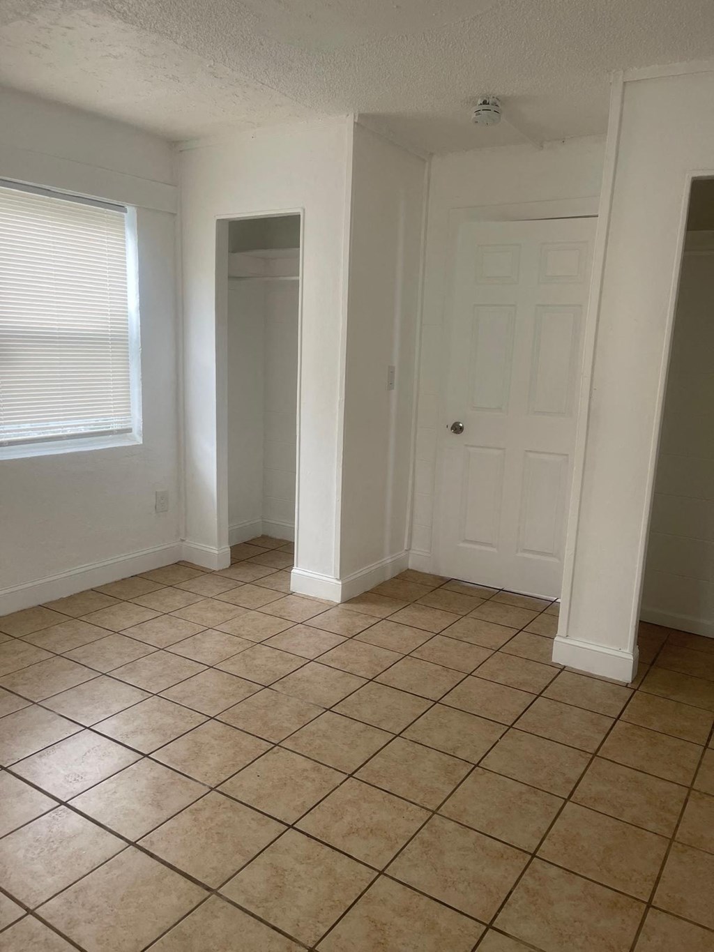 A room with a white door and a window with blinds.