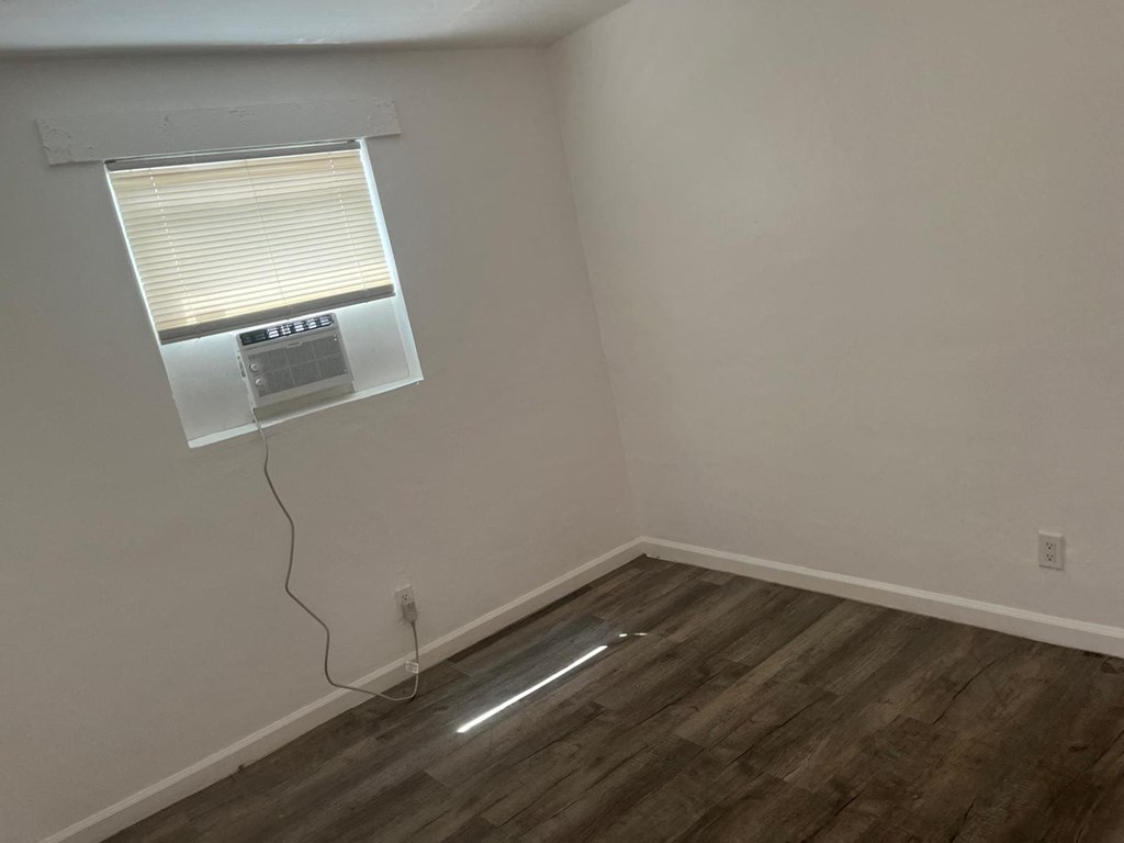 A room with a window and a wooden floor.