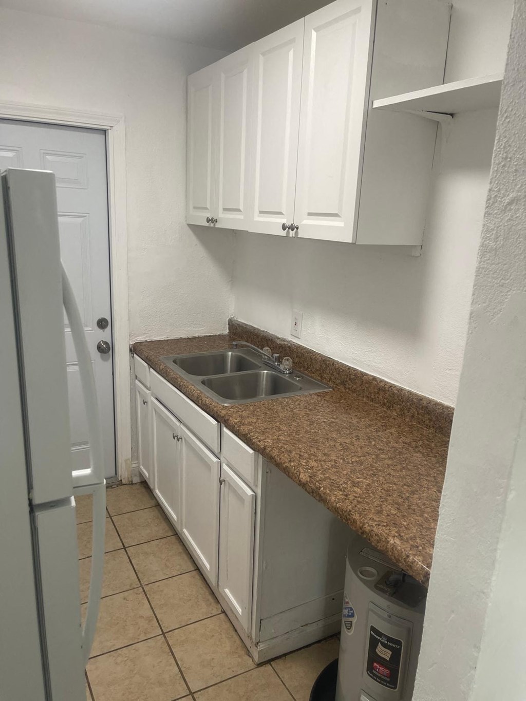 A kitchen with white cabinets and a granite counter.