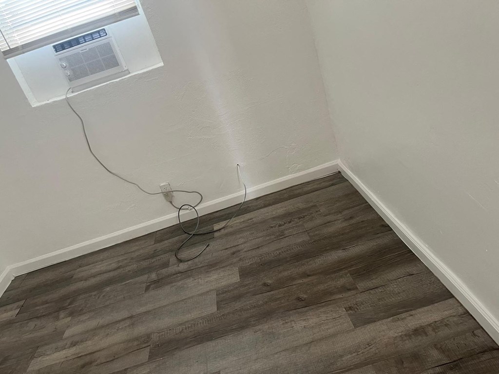 A room with a window and a wooden floor.