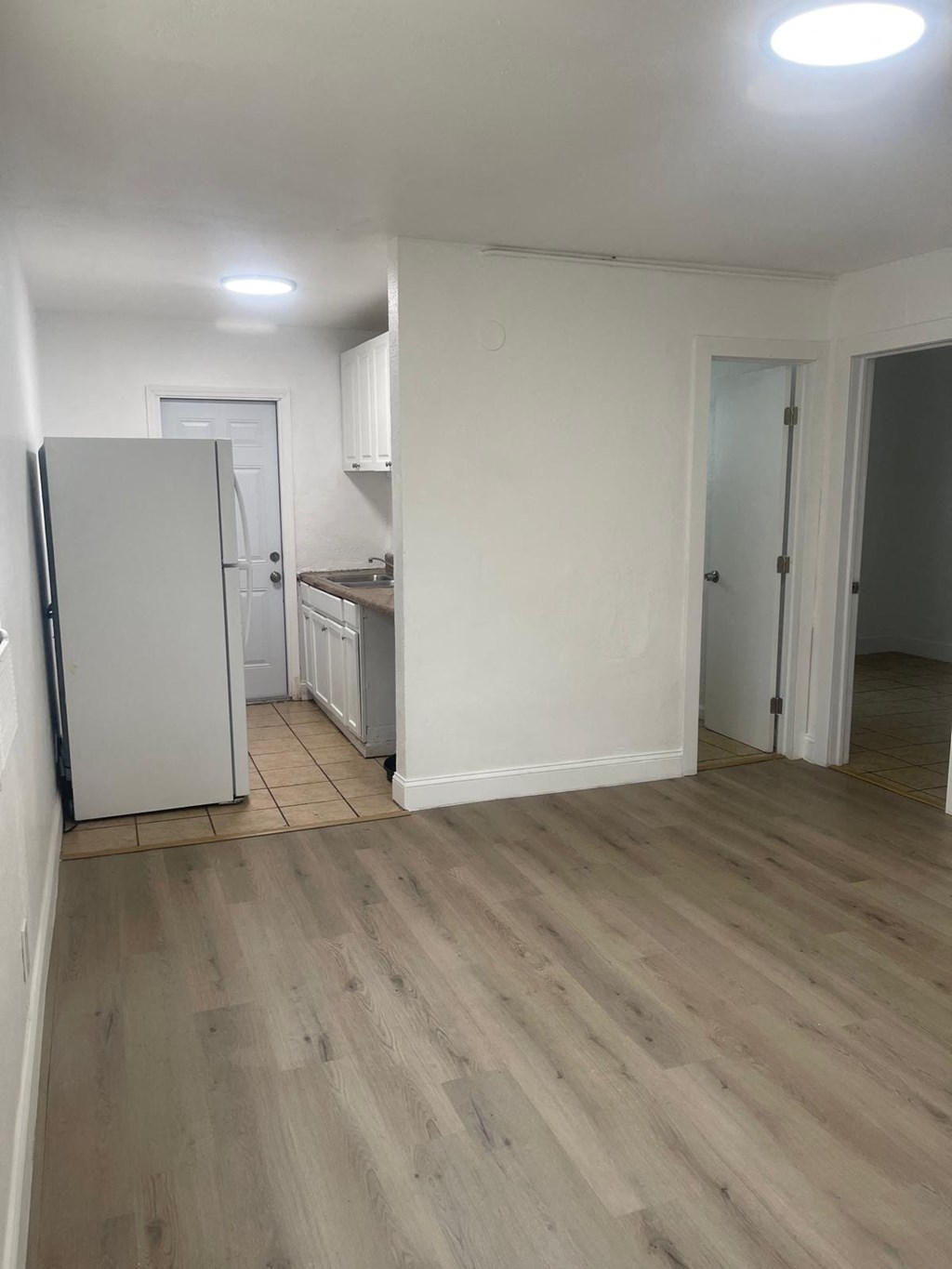 A kitchen with a white fridge and wooden floors.