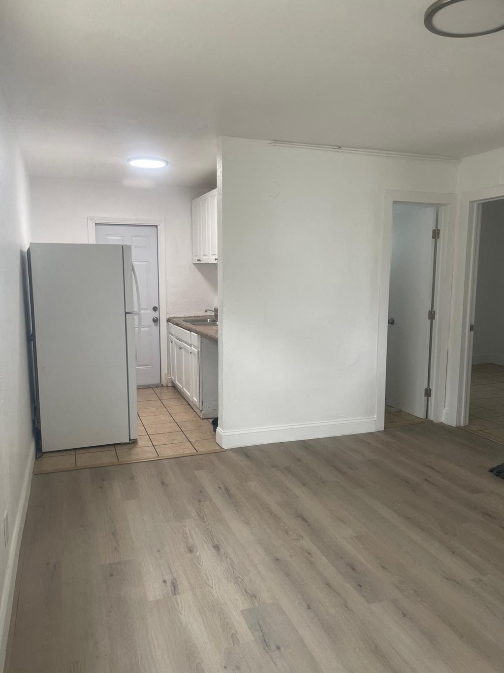 A kitchen with a white fridge and wooden floors.