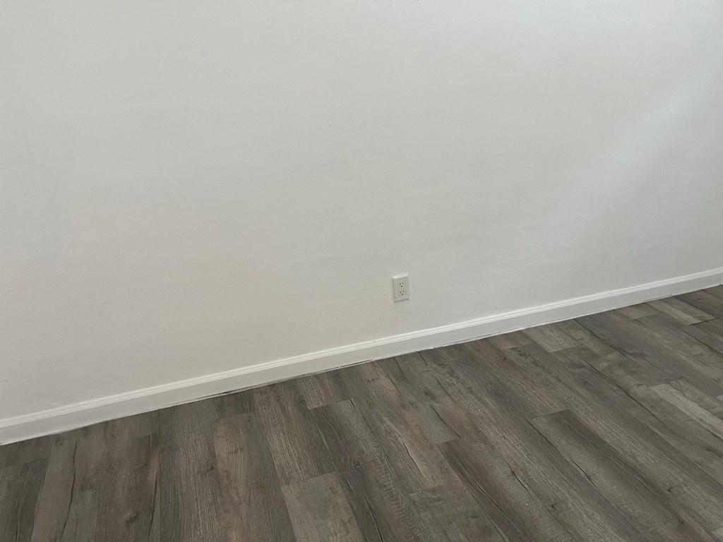 A room with a wooden floor and a white wall.