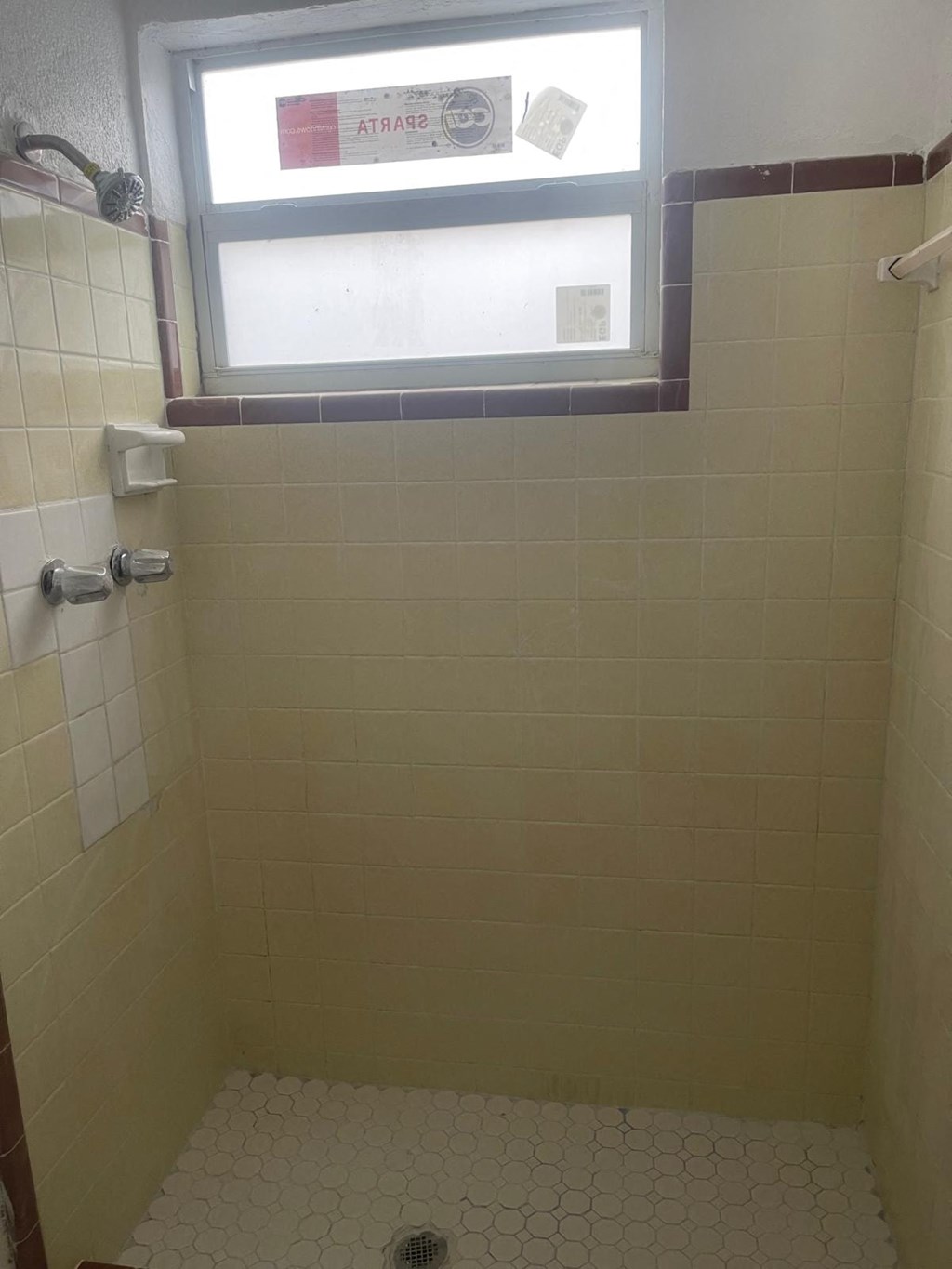 A small bathroom with a window and a shower.