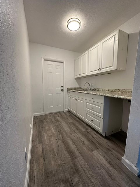 A kitchen with white cabinets and a wooden floor.